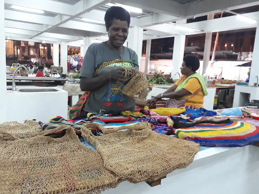 Mama merajut noken sambil berjualan di pasar
